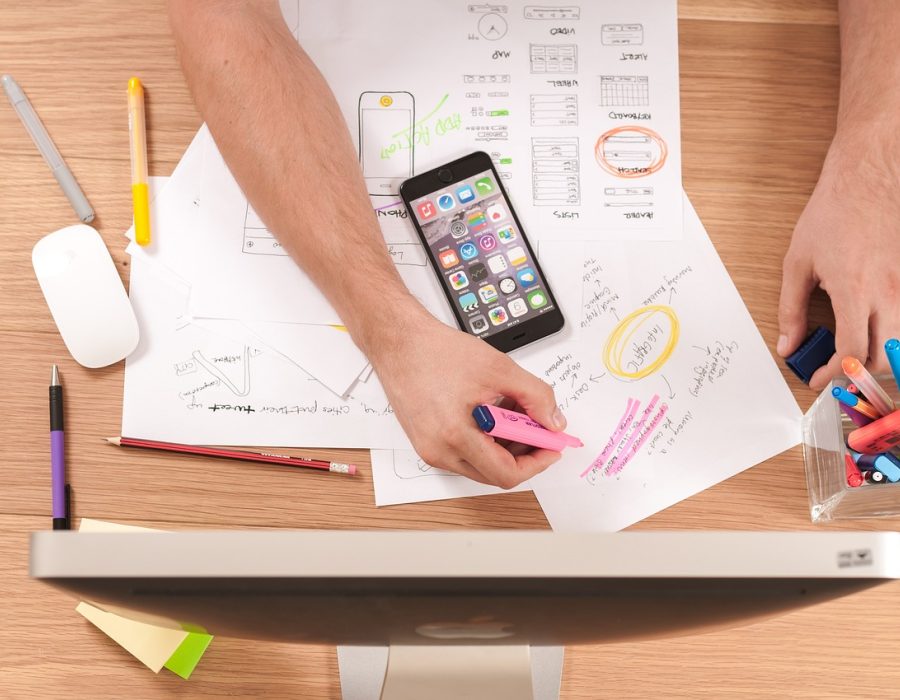 浅米色桌面上一部竖立的手机，屏幕显示 e站绿色版 客户端首页资源列表，旁边放着纸笔与一杯清茶，北欧性冷淡风格的自然光室内场景